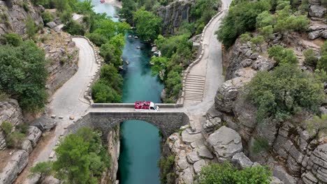 aerial view of a stone bridge over a turquoise river in a canyon