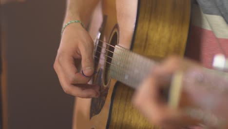 primer plano de un músico profesional tocando notas en una guitarra occidental con una púa de guitarra durante una sesión en vivo con cálidas luces de estudio