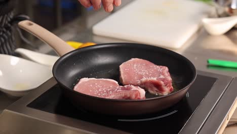 chef seasoning pork chops in a pan