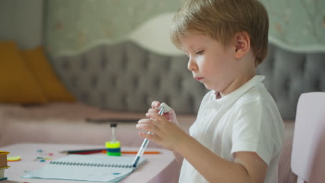 niño pequeño juega con pluma y borrador sentado en el escritorio