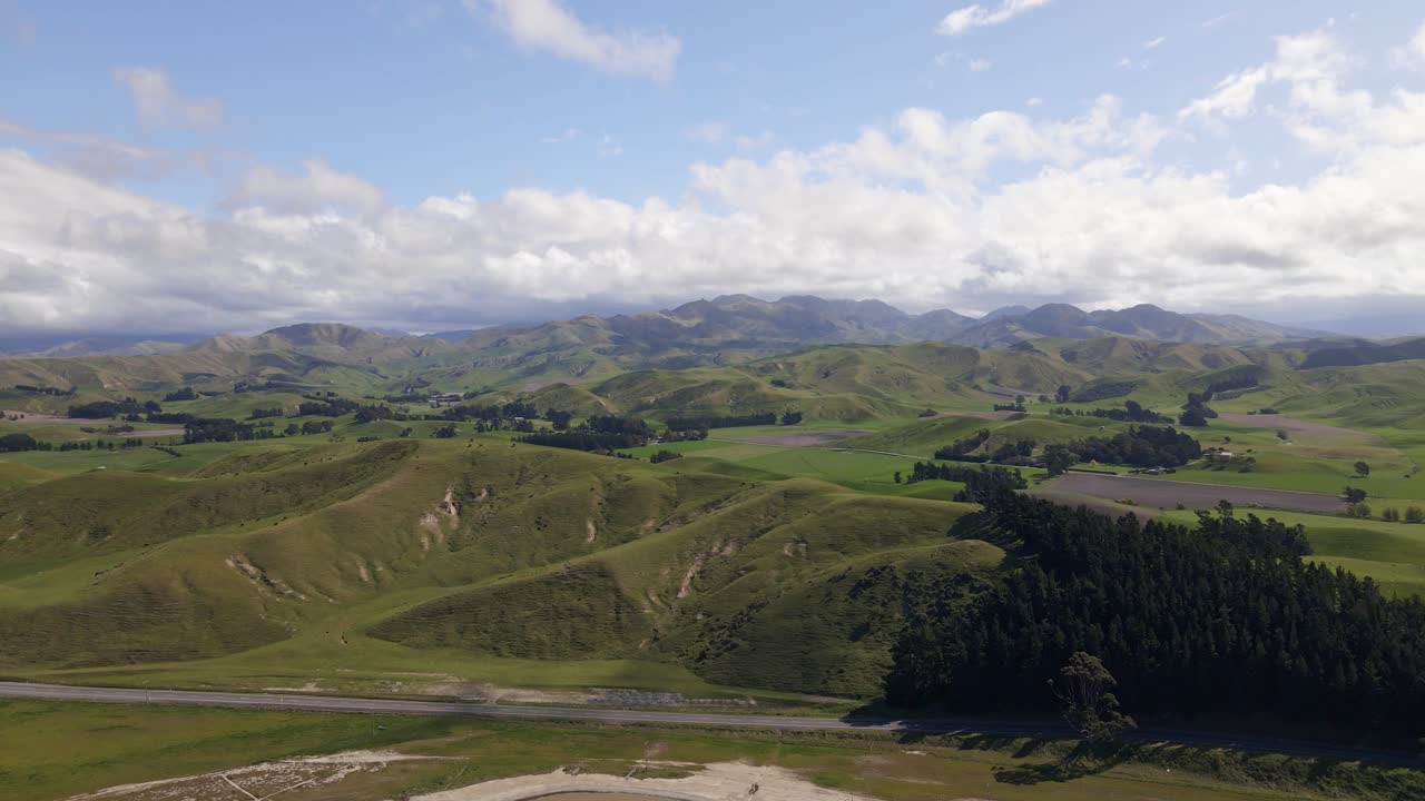 vista panorámica de una carretera rural que serpentea a través de las exuberantes y verdes colinas de marlborough, nueva zelanda, bajo un cielo soleado