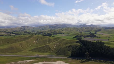vista panorámica de una carretera rural que serpentea a través de las exuberantes y verdes colinas de marlborough, nueva zelanda, bajo un cielo soleado