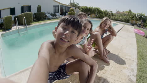 boy making selfie of himself and his friends at swimming pool.