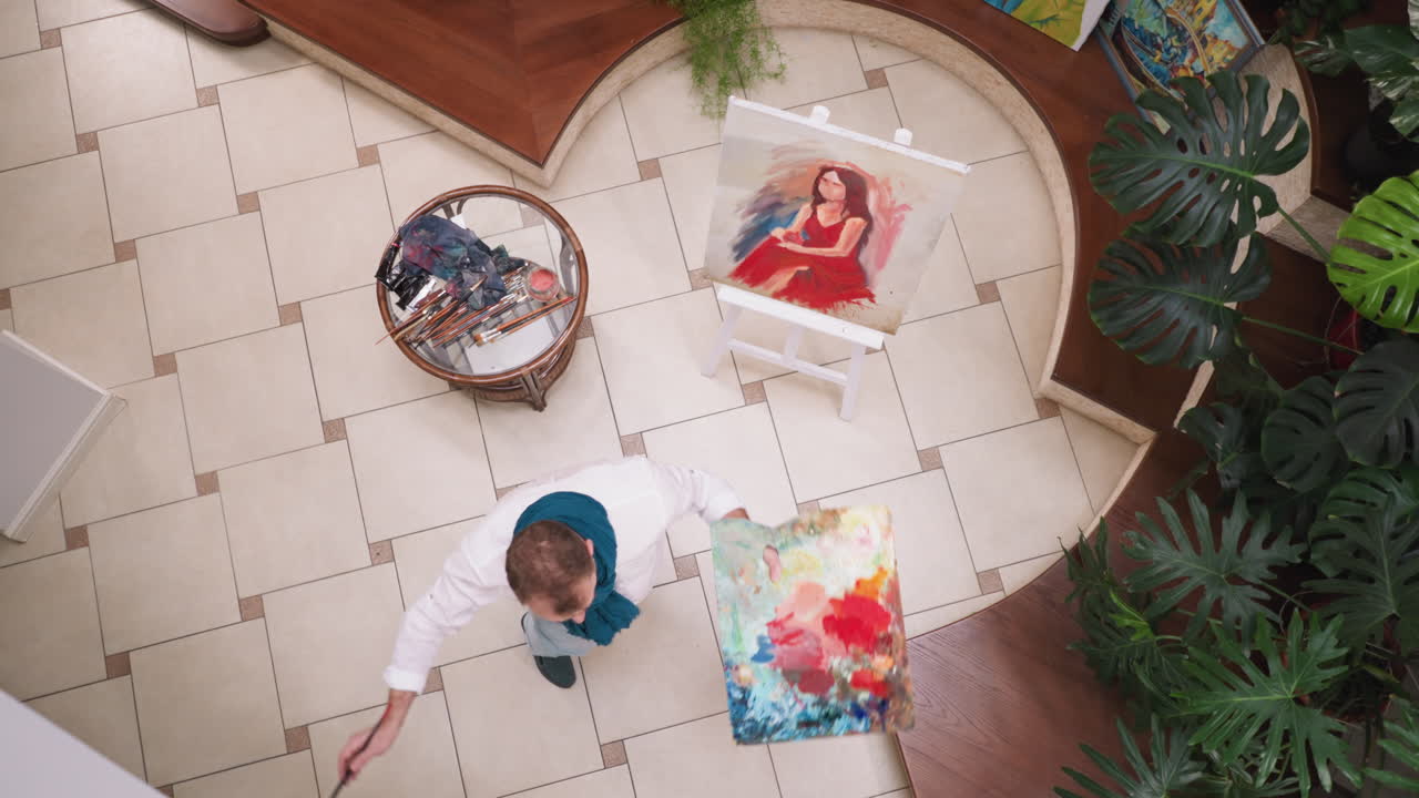 artista baila por retrato de mujer en el estudio. pintor alegre con paleta y pincel se da la vuelta mientras trabaja en la galería. diseñador con inspiración creativa