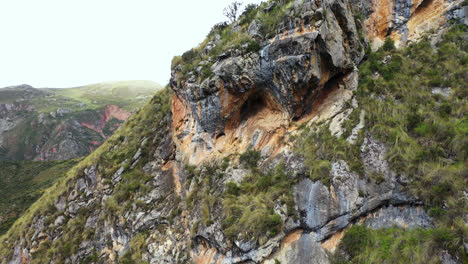 beautiful shot with drone zoom in to a cave on top of a mountain with vegetation in millpu located in ayacucho, peru