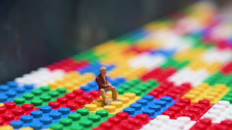 a small figure depicting a man sitting down is placed on top of a colorful lego bricks game