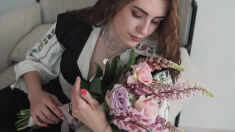 portrait-depicts-a-young,-beautiful-woman-in-authentic-Ukrainian-embroidered-attire-holding-a-bouquet-of-live-flowers-and-reclining