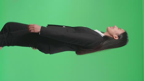 vista lateral de una mujer de negocios asiática sonriente caminando a través de la pantalla verde en el estudio