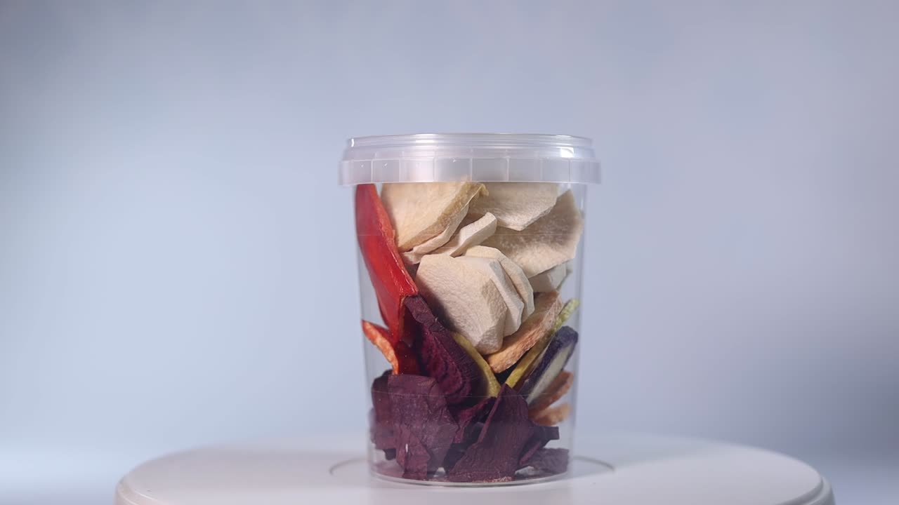 A transparent jar filled with a colorful assortment of freeze-dried fruits and vegetables, including blueberries, cranberries, raspberries, apple slices, pumpkin cubes, and more.