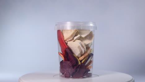 a transparent jar filled with a colorful assortment of freeze-dried fruits and vegetables, including blueberries, cranberries, raspberries, apple slices, pumpkin cubes, and more.
