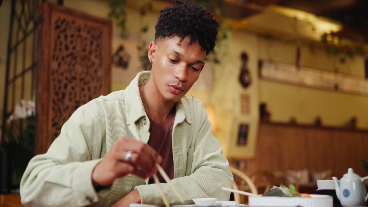 Homem comendo com hashi em ambiente interno