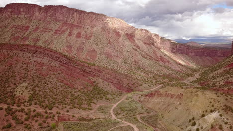 Antenne-Der-Unbefestigten-Straße-Mit-Butte-Mesa-Flat-Top-Mountain-An-Einem-Schönen-Tag-In-Der-Wüste-Im-Südwesten-Von-Colorado,-USA