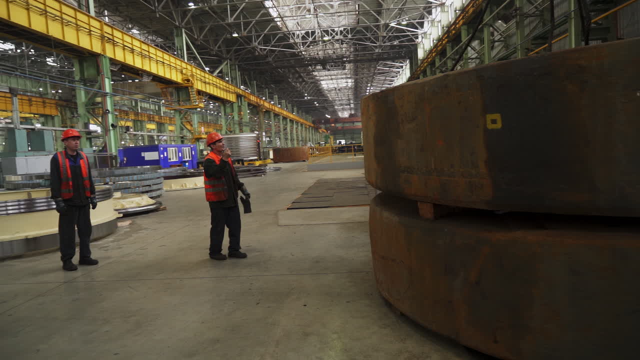 Workers Inspecting Large Metal Disks in a Factory