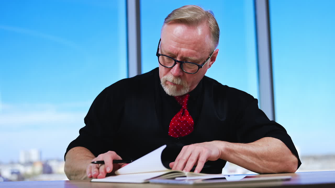 Hard-working man writing in the paper notebook. Businessman turns the pages looking for some notes.