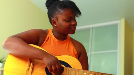 african american teenage girl practicing her skill on acoustic guitar