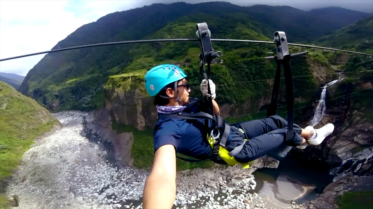 hombre joven viaja en tirolesa por las montañas verdes en ecuador, selfie disparado