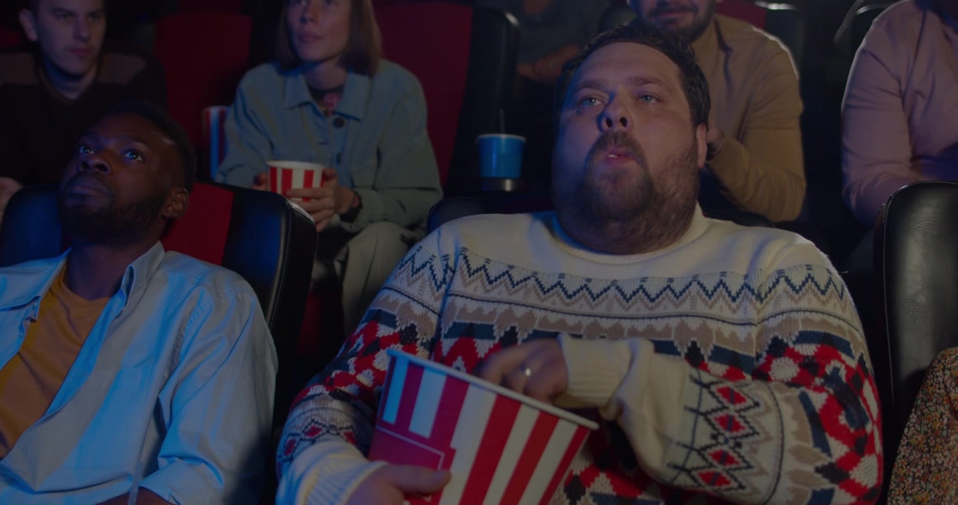Uomo che mangia popcorn mentre guarda un film al cinema