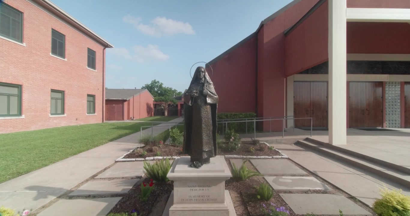 Um dolly lento em direção a uma Igreja Católica durante a Santa Missa com uma estátua de Santa Teresinha do Menino Jesus à frente