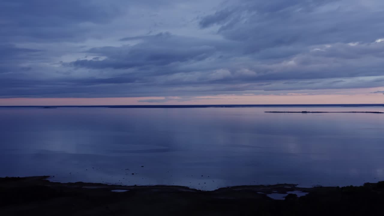 Panning view of a cloudy sky over a calm sea during sunset