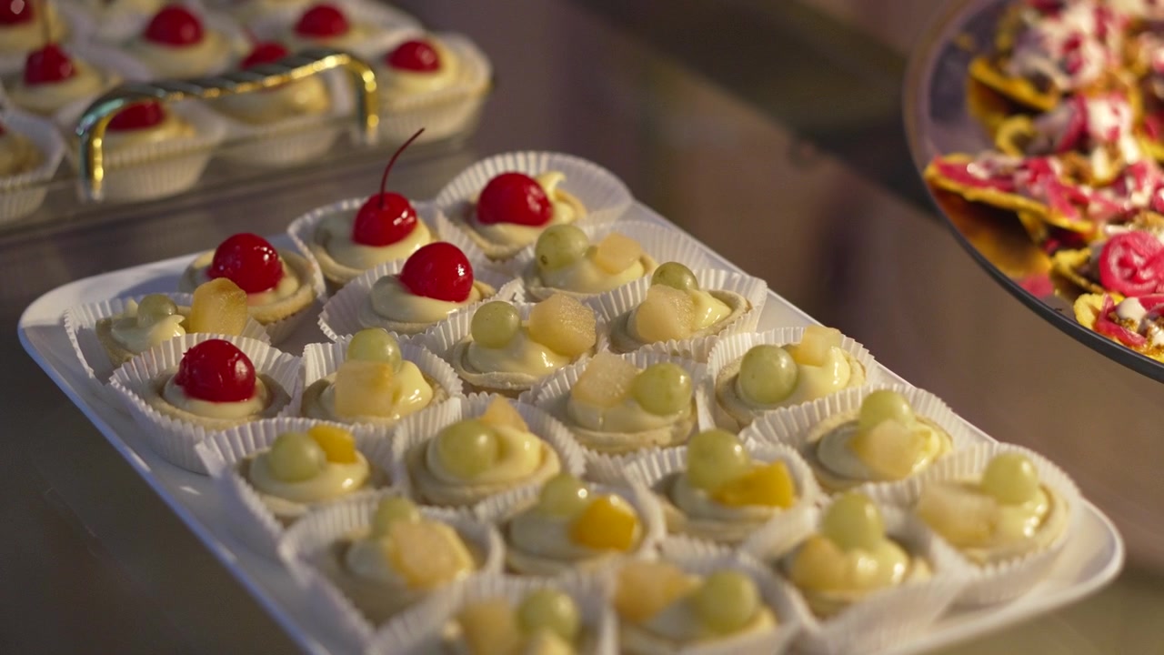 Nærbillede af et udvalg af mini-frugttærter på et sølvfad ved en elegant buffetreception.