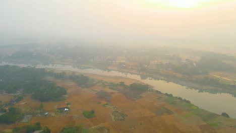 An-aerial-view-flying-over-the-Surma-river-and-farmland-on-a-foggy-misty-morning