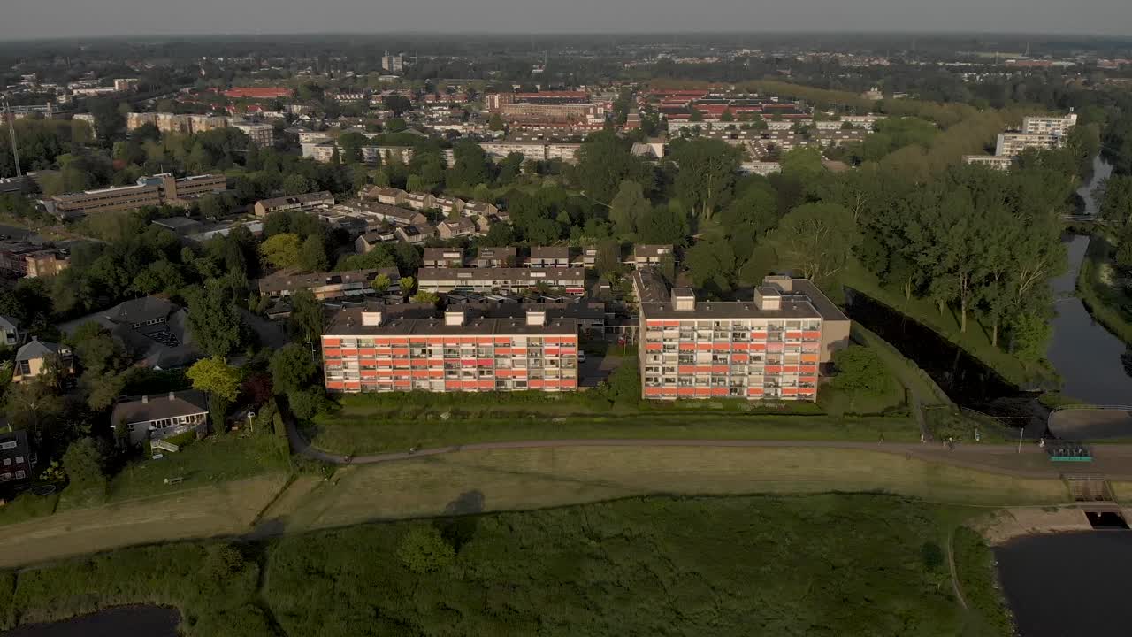 enfoque aéreo del paisaje urbano con sombrillas naranjas cerradas de edificios de apartamentos de gran altura a lo largo del río ijssel en un lento movimiento hacia atrás que revela el paisaje de las llanuras aluviales holandesas en zutphen