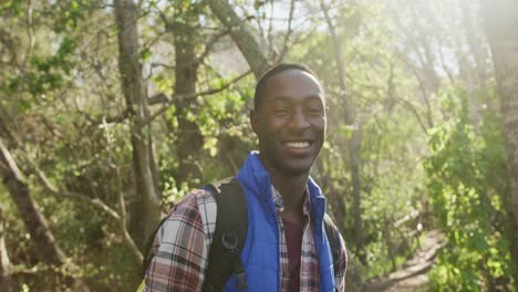 retrato de un hombre afroamericano sonriente en el bosque durante una caminata en el campo