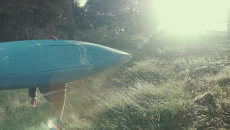 Adventure-kayaker-carrying-canoe-through-meadow