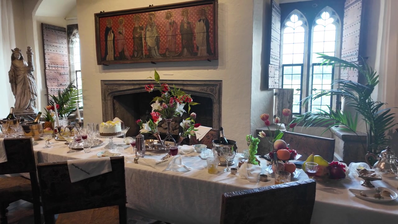 Elegant dinner table inside Leeds Castle with flowers, fruit and gothic window.