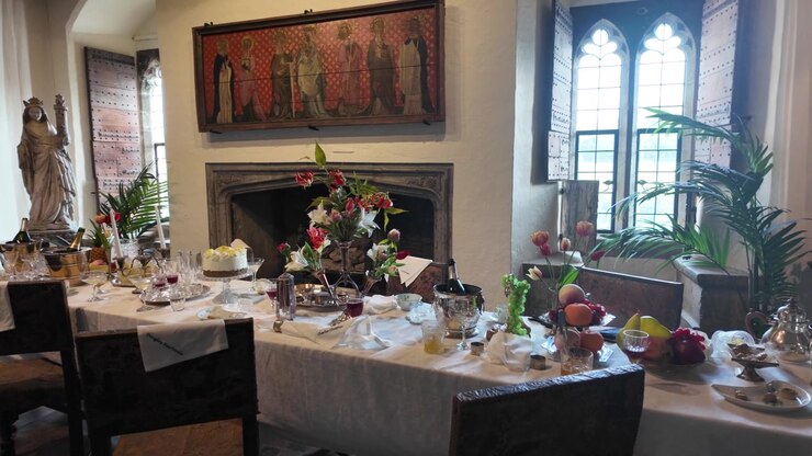 Elegant dinner table inside Leeds Castle with flowers, fruit and gothic window.