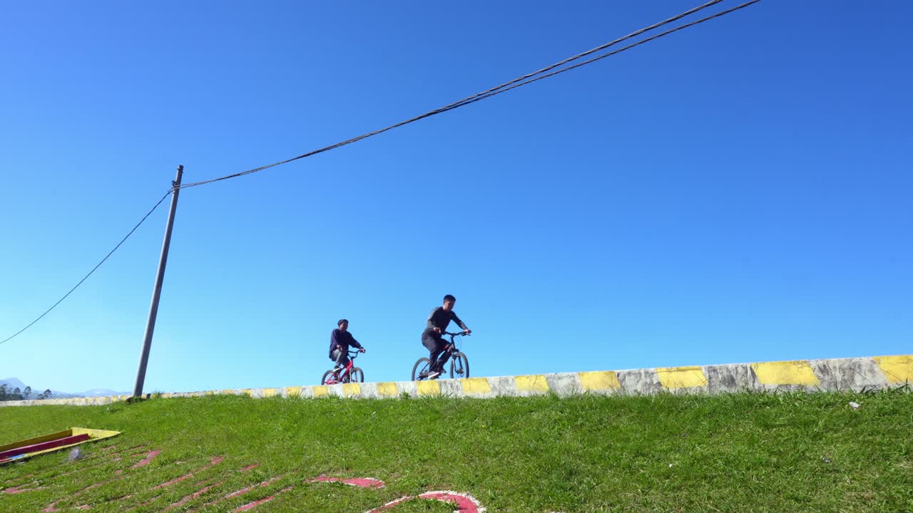 Two Young Men Ride Bicycles And Enjoying Outdoor Adventure Under Clear Blue Sky