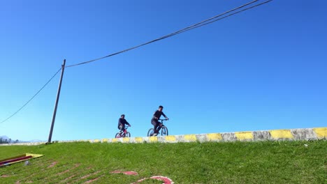two young men ride bicycles and enjoying outdoor adventure under clear blue sky