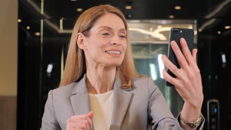 hermosa mujer de negocios positiva haciendo una videollamada sonriendo y hablando con su socio de negocios. mujer de negocios teniendo una videochat discutiendo, trabajando en línea reuniéndose con el equipo en la sala de la oficina.