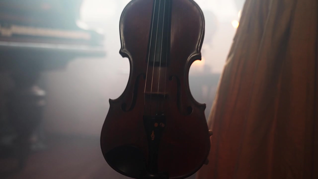 Violino vintage in una stanza suggestiva illuminata a lume di candela con pianoforte