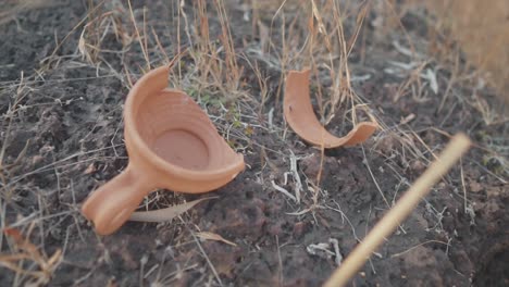 tiro suave en cámara lenta de cerámica de arcilla roja india tradicional rota con dos fragmentos sobre un montículo de tierra, junto a una profundidad de campo poco profunda de la olla