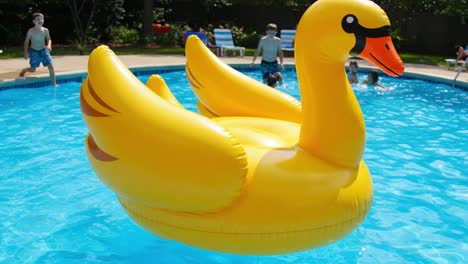 a fun day by the pool featuring a bright yellow inflatable duck float with kids swimming and enjoying their time in the water on a sunny day