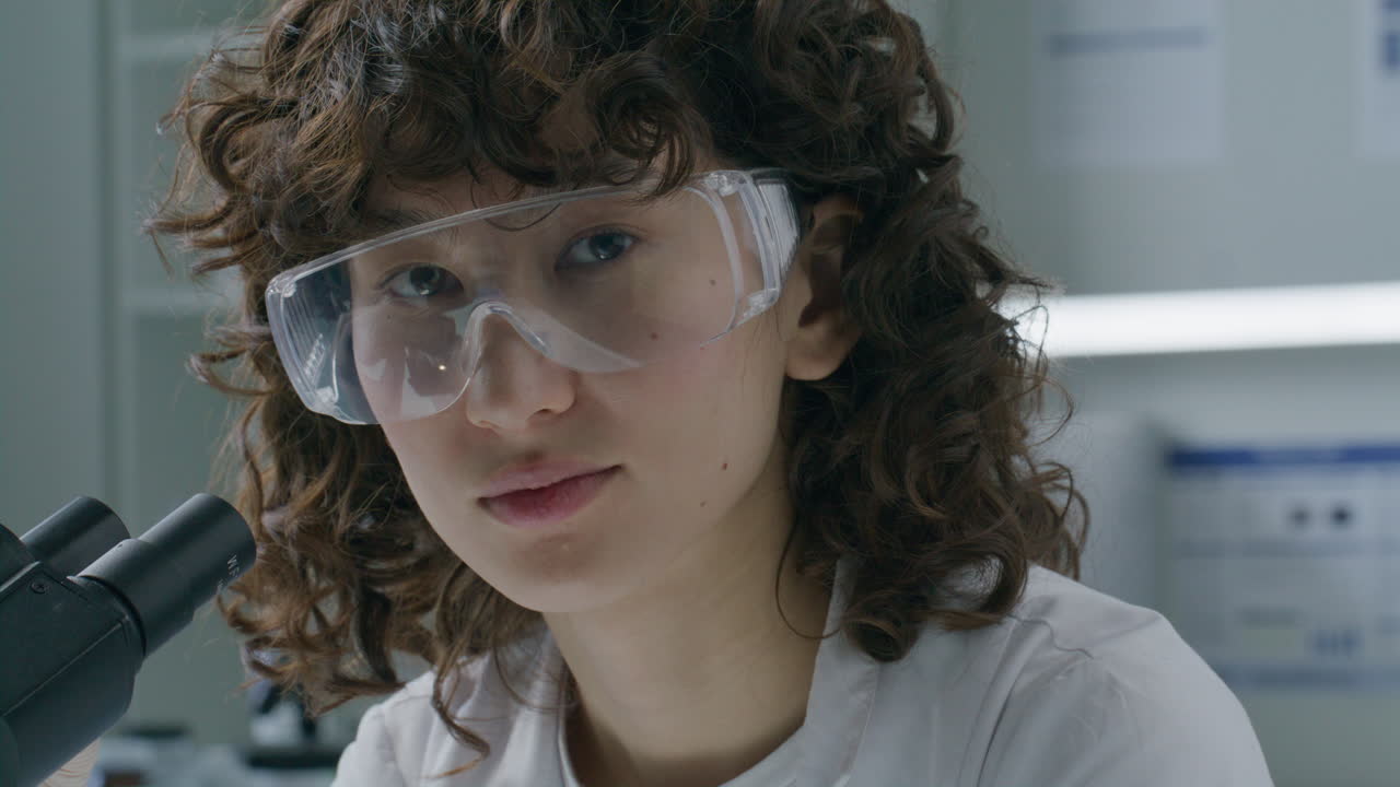 Portrait of Young Female Scientist with Microscope in Laboratory