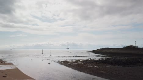 Scottish-river-flowing-into-the-sea-at-low-tide-with-a-duck-running-on-the-water-before-takeoff