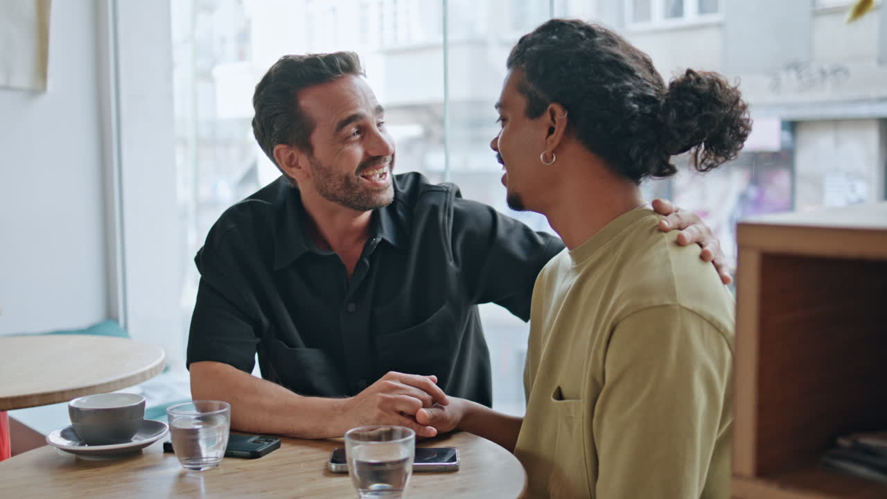 Cheerful lgbt lovers laughing joking at romantic meeting in cafe close up.