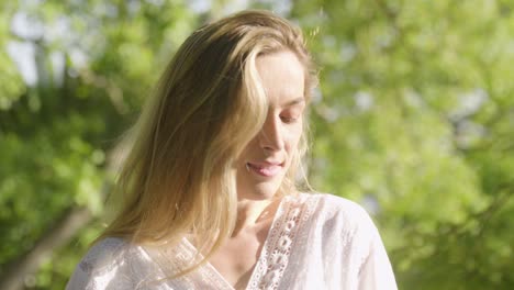 portrait of a young, charming blonde woman in a white dress posing to the camera