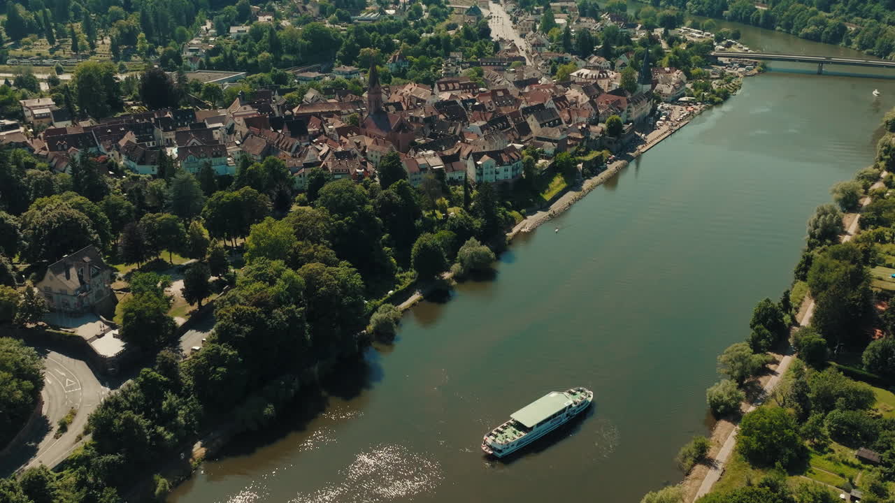 Aerial reverse ascending view of beautiful boat sailing through canal and revealing the cityscape of Odenwald, Germany