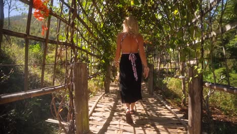 hermosa mujer europea caucásica rubia caminando sobre un puente de bambú en el pueblo de montaña pai en tailandia en un cálido día de verano