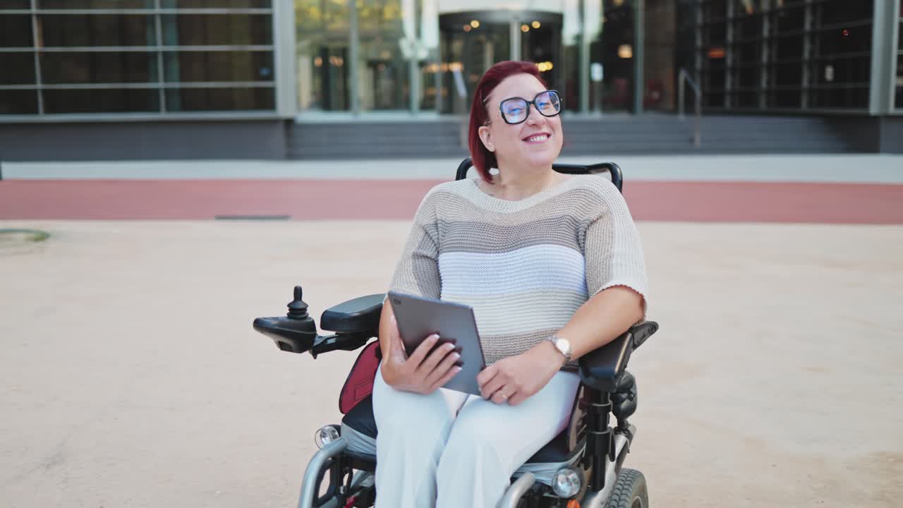 Happy Woman in Motorized Wheelchair Holding Tablet Outdoors