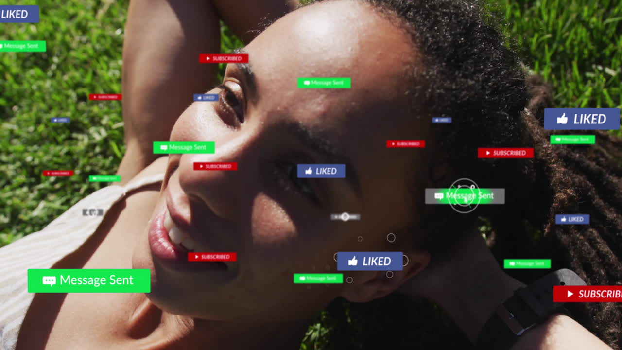 Lying on grass, person receiving animation of social media notifications overlaying