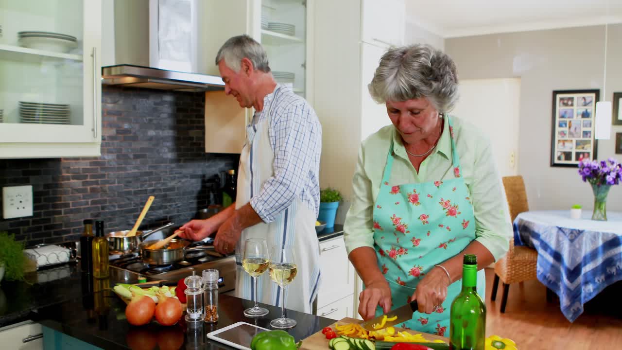 Coppia di anziani che assaggia il cibo che sta cucinando in cucina 4k