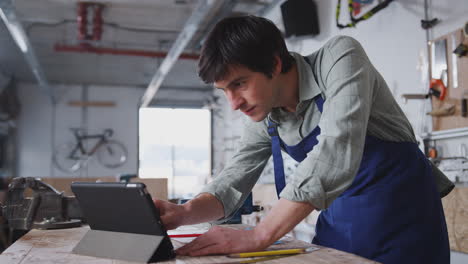 male business owner in workshop for building bicycles using digital tablet