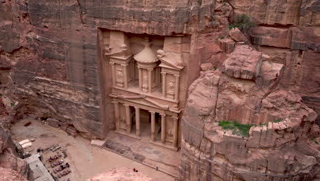 sight of al khazneh or the treasury nabatean temple cut out of sandrock of hellenistic period in ancient city of petra from uphill with tourists on the ground