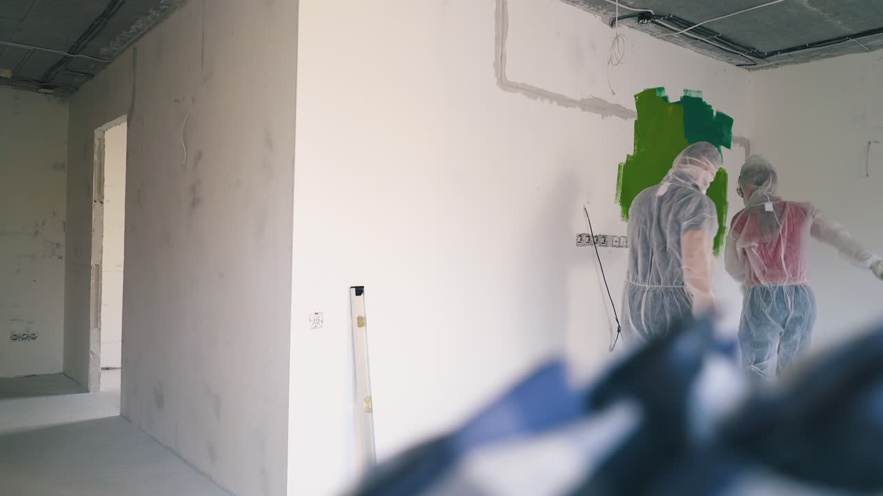 funny family in workwear comes up to green spot on wall