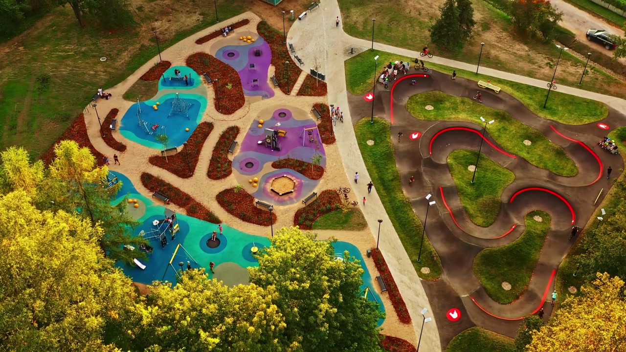 Moderno complejo de actividades con parque infantil y pista de pump track en verano, vista aérea a la luz del sol de la hora dorada.