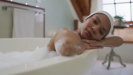 Portrait-of-mixed-race-woman-taking-a-bath-looking-at-camera